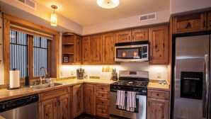 Une cuisine dotée de meubles en bois, d’appareils électroménagers en acier inoxydable et d’un plan de travail en granit.