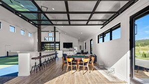 A spacious indoor area with a ping pong table, seating, and a view through large windows.
