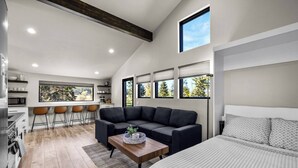 A modern interior with a kitchen, dining area, and a large bed. - Paddles Up Private Pickleball Retreat (Whitefish)