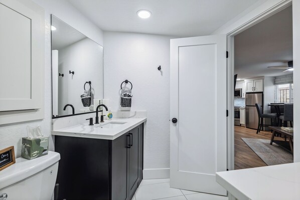 A modern bathroom with a white sink, black cabinets, and a large mirror.