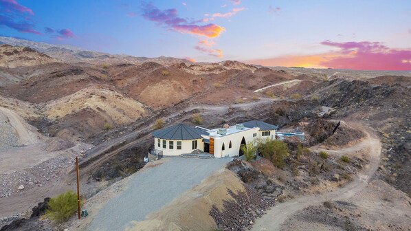 A modern house with a circular design, surrounded by rugged terrain and a clear sky. - Charming 1-bedroom with stunning Views (Lake Havasu City)