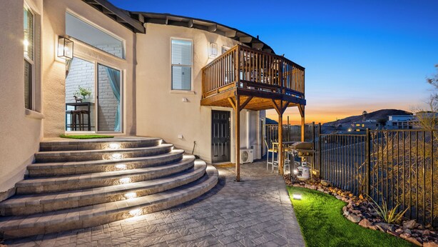 A modern house with a curved staircase leading to a wooden deck.