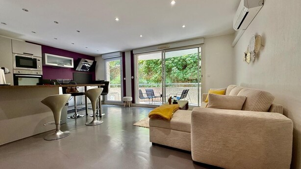 A modern living room with a sofa, a coffee table, and a dining area with chairs and a table.