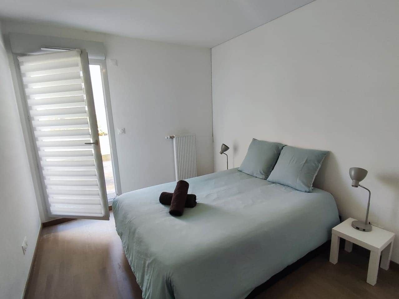 A bedroom with a bed, a nightstand, a lamp, and a radiator.