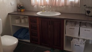Un baño con inodoro, lavamanos y repisas con toallas.
