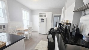 Une cuisine moderne avec un plan de travail noir, des meubles blancs, une cuisinière et un coin repas comprenant une table et des chaises.