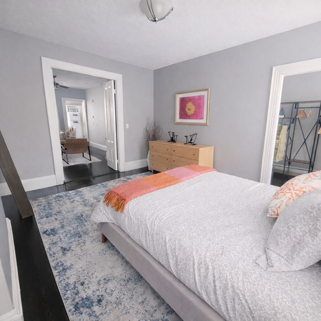 A bedroom with a bed, dresser, and a framed picture on the wall.