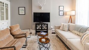 Ein Wohnzimmer mit einer Couch, einem Couchtisch, einem Fernseher und einer Lampe.