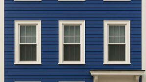 Un bâtiment à l’extérieur bleu, avec des encadrements de fenêtres blancs et une porte noire portant le numéro 28.