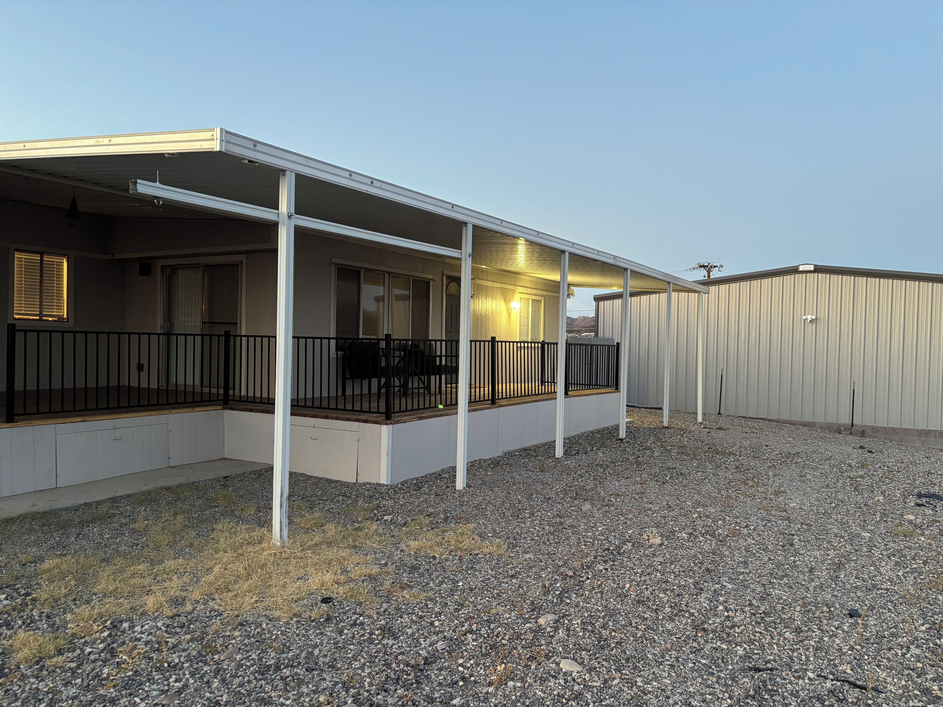 A covered outdoor area with a patio, a fenced deck, and a gravel ground.