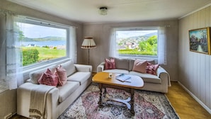 A cozy room with two sofas, a small table, and a view of a green landscape through large windows. - Awesome home in Fitjar with WiFi (Fitjar)