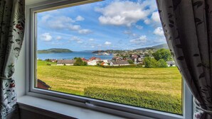 A window view of a coastal town with houses, a body of water, and hills in the distance. - Awesome home in Fitjar with WiFi (Fitjar)