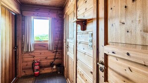 Un corridoio in legno con un estintore, una finestra con tende e una porta con maniglia.