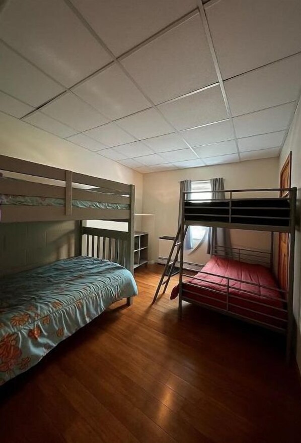 A room with two bunk beds, wooden flooring, a desk, and a window with curtains. - Lake Living, sit back and relax! (Middleton)