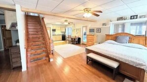 Une chambre spacieuse avec un lit en bois, un banc et un ventilateur de plafond.