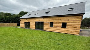 A modern wooden house with a sloped roof and large windows.