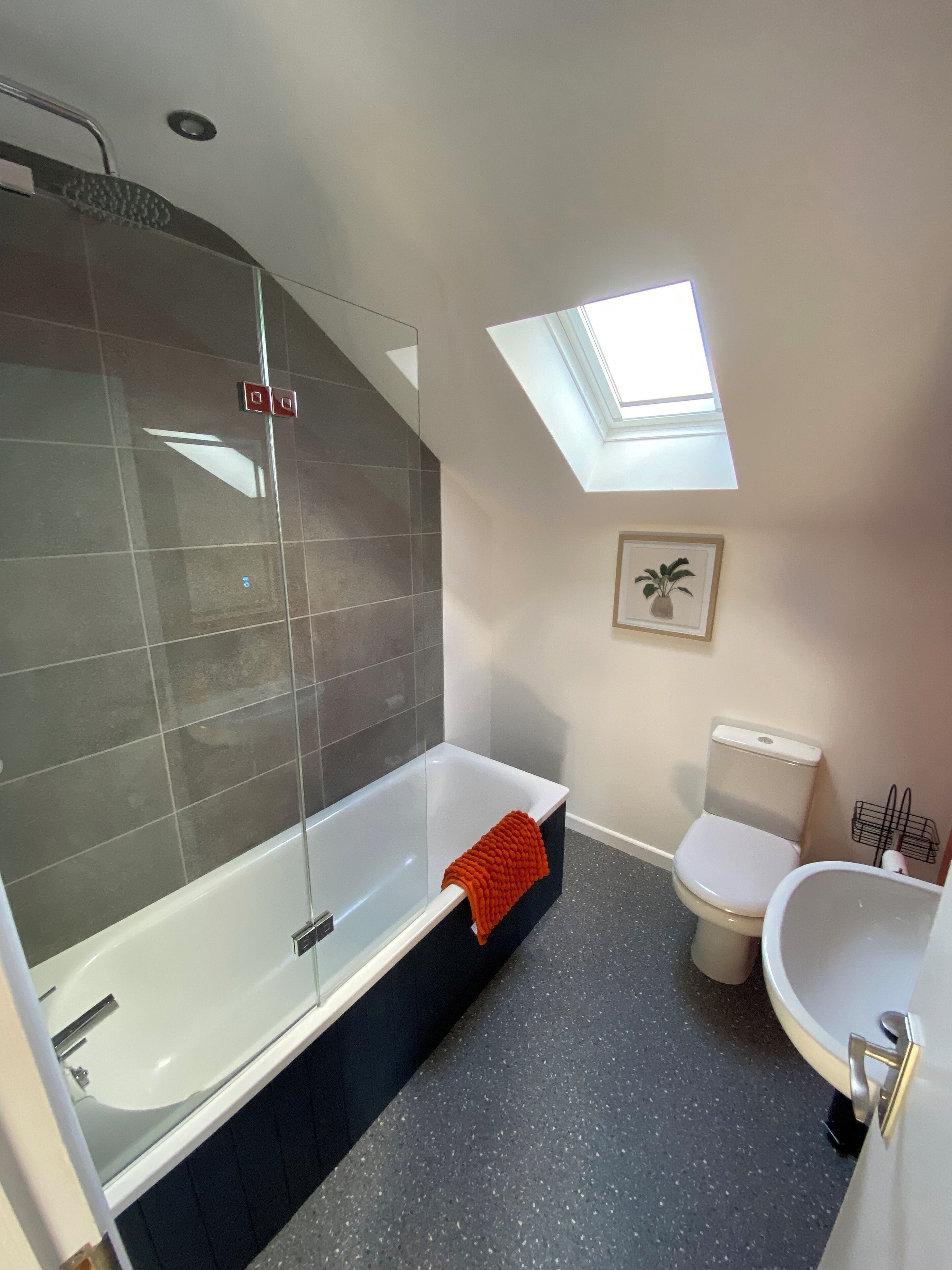 A modern bathroom with a glass-enclosed shower, a freestanding bathtub, a toilet, and a sink.