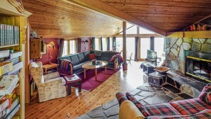 A cozy living room with a stone fireplace, wooden ceiling, and a large window. - Awesome home in Uvdal with sauna (Uvdal)