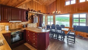 A wooden cabin with a kitchen and dining area, featuring a large island, wooden cabinets, and a view of the outdoors. - Cozy home in Hemsedal with sauna (Hemsedal)