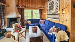 A cozy room with a blue sofa, wooden walls, a fireplace, and a large tapestry. - Cozy home in Hemsedal with sauna (Hemsedal)