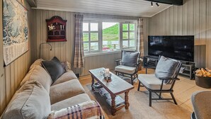 Un salon confortable avec un canapé, des fauteuils, une table basse et un téléviseur.