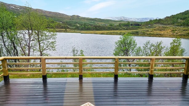 Une terrasse en bois offrant une vue sur un lac et des montagnes.