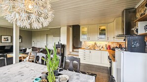 A modern kitchen with white cabinets, a dining area with a table and chairs, and a unique ceiling light fixture. - Amazing home in Edland with sauna (Edland)