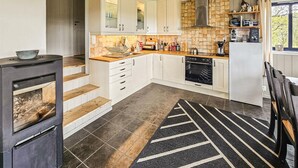 A modern kitchen with white cabinets, a built-in oven, and a black stove. - Amazing home in Edland with sauna (Edland)