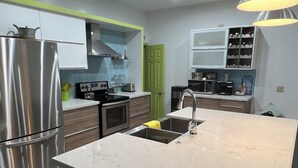Een moderne keuken met een centraal eiland, roestvrijstalen apparatuur en een groene deur.