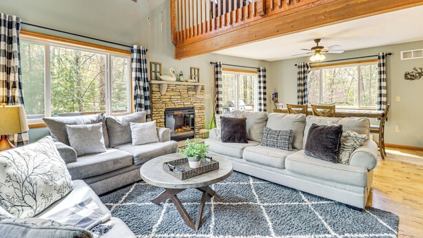 A spacious living room with a fireplace, two sofas, a coffee table, and a dining area with a wooden ceiling and large windows. - Game Room + Lake Access: Albrightsville Escape (Albrightsville)