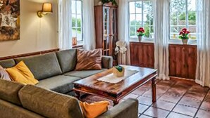 A cozy living room with a green sofa, a wooden coffee table, and a large window with curtains. - Lovely home in Lindesnes with sauna (Lindesnes)