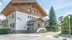 A two-story building with a stone facade and wooden upper levels, featuring a staircase and a balcony. - Studio Montée du Calvaire - Welkeys (Megève)