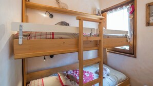 A bunk bed with a ladder, a small shelf, and a window with curtains. - Studio Montée du Calvaire - Welkeys (Megève)