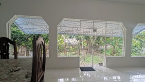 A room with large windows, a bed, and a chair. - Charming 3-bedroom house with AC, WiFi in wonderful Tower Isle (Tower Isle)