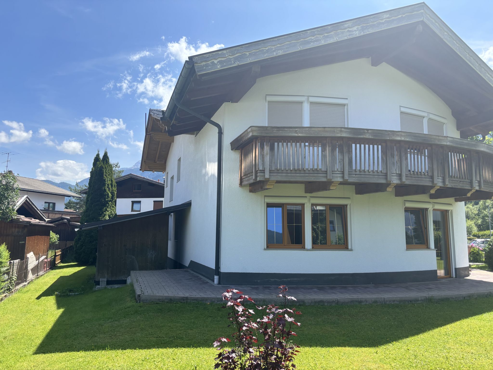 A two-story house with a balcony, a wooden fence, and a well-maintained lawn.