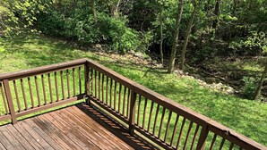 Una terraza de madera con barandilla y cuatro sillas de plástico.