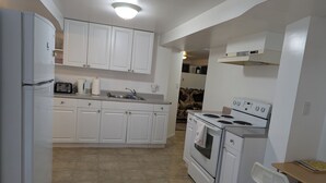 Una cocina con gabinetes blancos, un refrigerador, una estufa y un lavamanos.