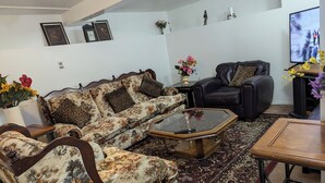 Una sala de estar con un sofá, una mesa de centro, un televisor y una alfombra.