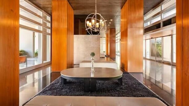 A modern interior with a round table, a hanging light fixture, and large windows.