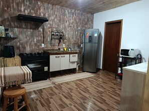 A compact kitchen with a built-in stove, a refrigerator, and a microwave. - Refugio Jaguary Country House (Monte Verde)
