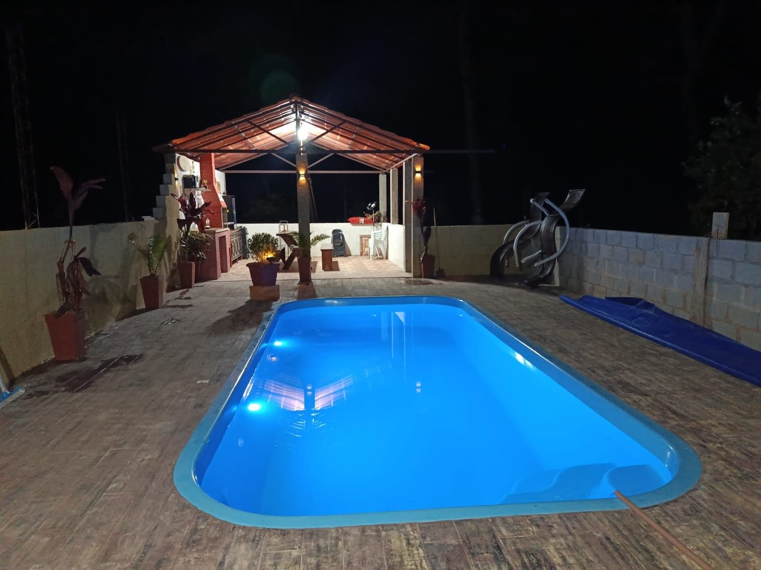 A swimming pool with a wooden deck and a covered seating area.
