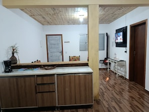 A kitchen with wooden cabinets, a coffee maker, and a television on the wall. - Refugio Jaguary Country House (Monte Verde)