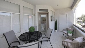 Un balcon avec une table ronde, des chaises et des plantes en pot.