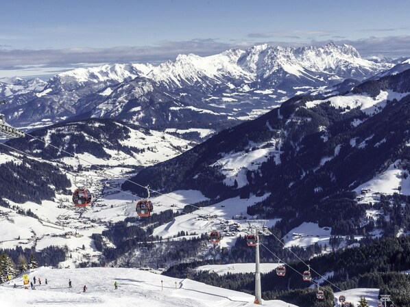 Une station de ski dotée de télésièges, de montagnes enneigées et d’un ciel dégagé.