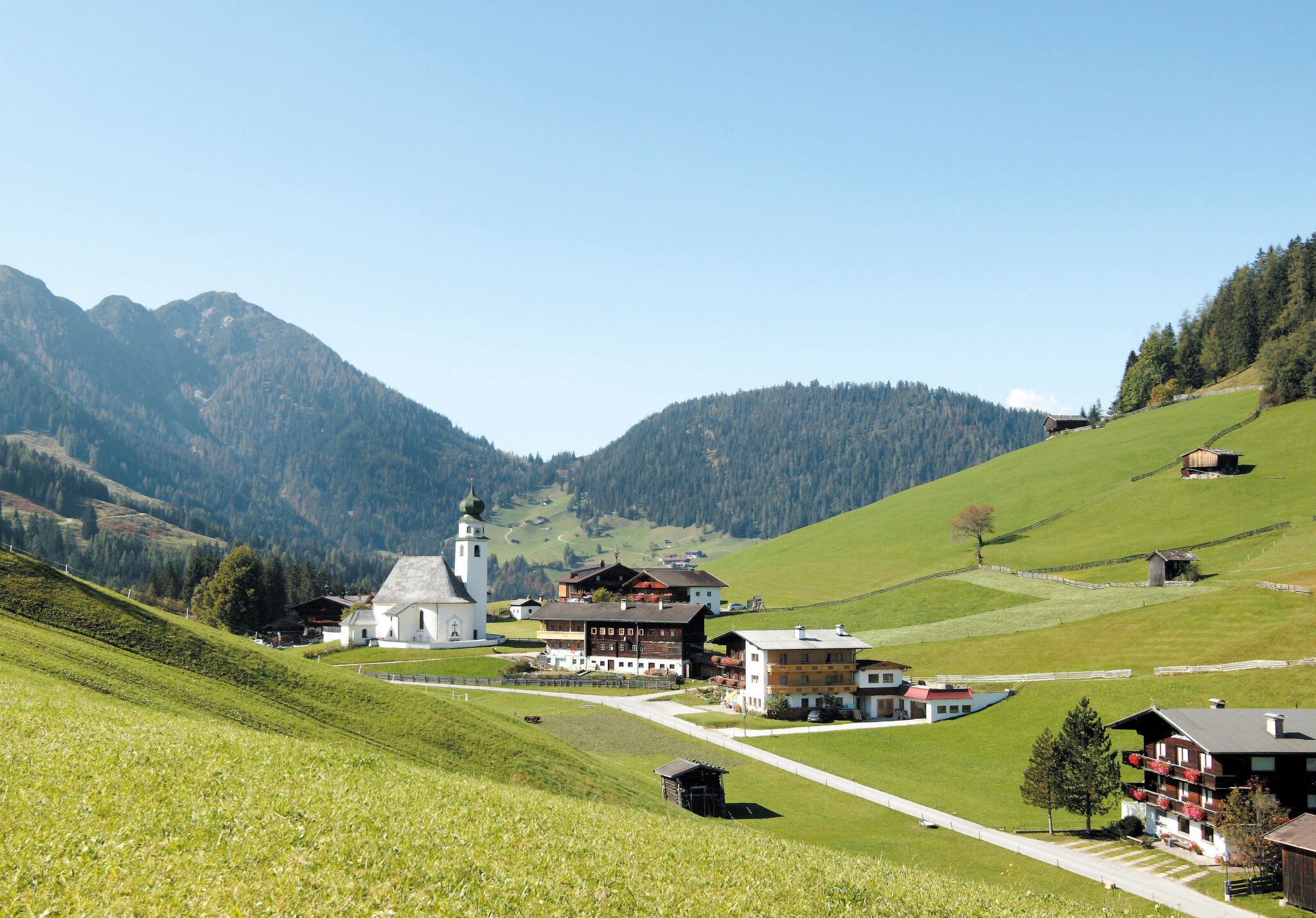 A rural village with a church, traditional buildings, and a hillside.