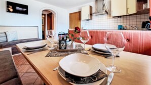 A dining area with a wooden table set for four, including plates, glasses, and cutlery. - Berganger by Interhome (Wildschönau)