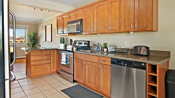 A modern kitchen with wooden cabinets, stainless steel appliances, and a granite countertop. - Sunny 1BR Apt in Suburb - Salem 3C rep (Arlington Heights)