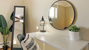 A room with a white desk, a round mirror, a small table lamp, a potted plant, and a large mirror. - Sunny 1BR Apt in Suburb - Salem 3C rep (Arlington Heights)