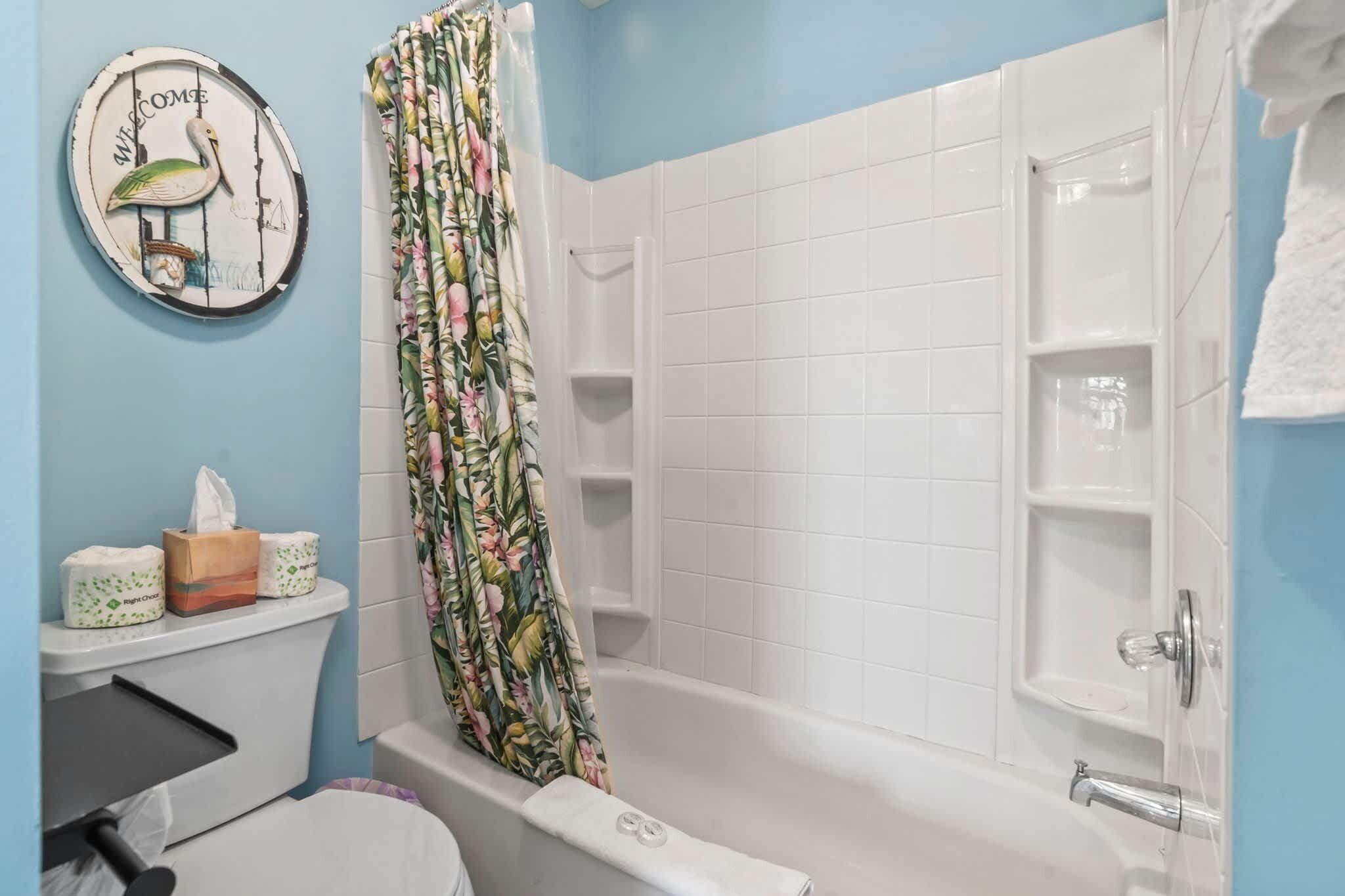 A bathroom with a shower, toilet, and a welcome sign.
