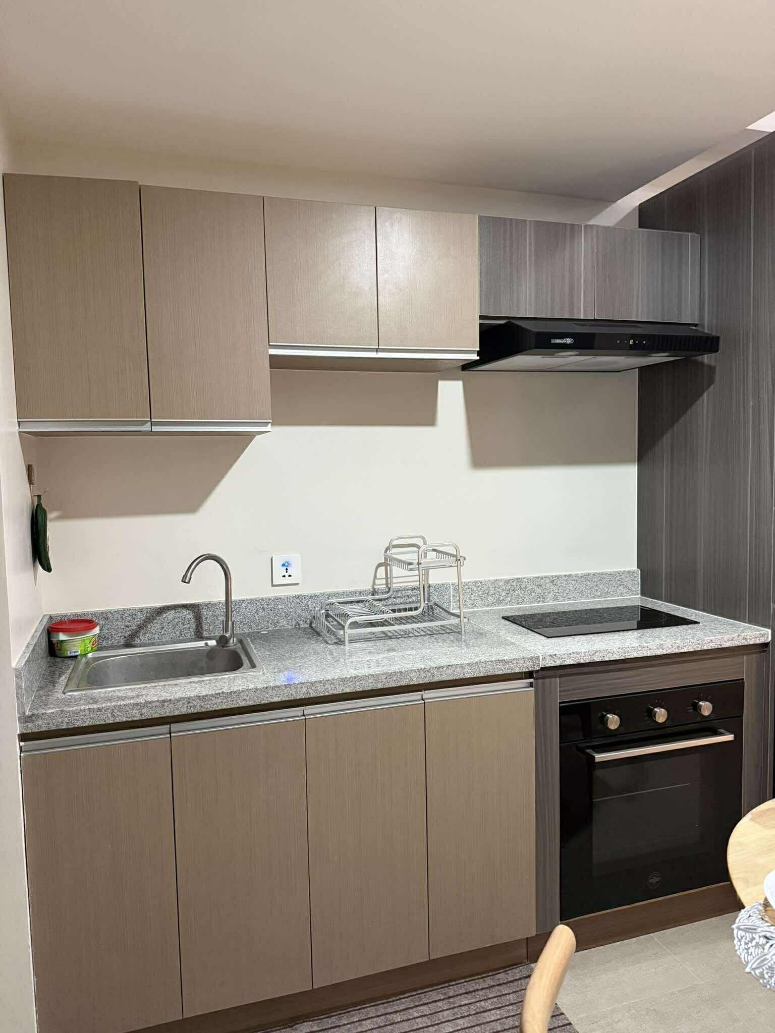 Een moderne keuken met een granieten aanrecht, een roestvrijstalen spoelbak en een zwarte afzuigkap.